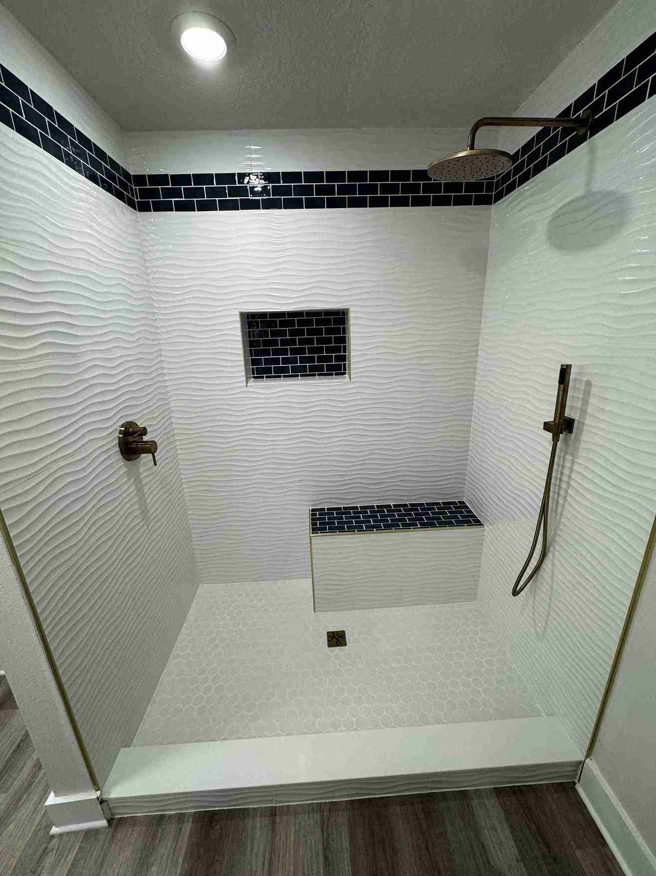 Custom white tile walk-in shower with dark accent, niche and bench by Barys Tile in Panama City Beach